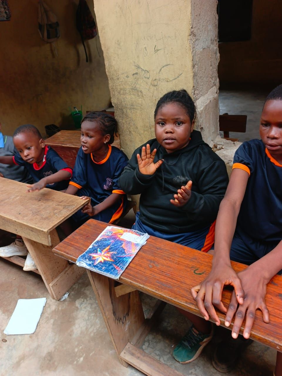 A primary pupil working at a wooden desk with a workbook